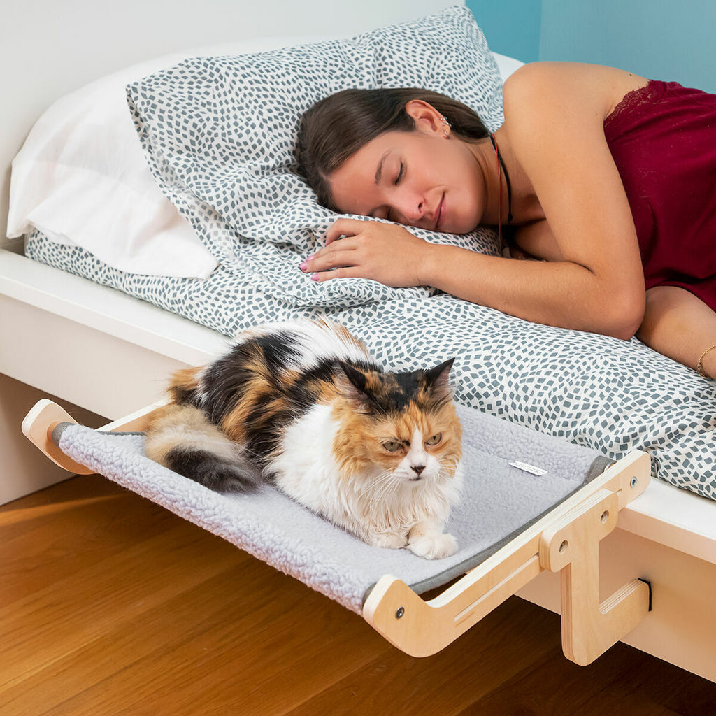Cama hamaca para gatos Nuzzo sujeta junto a la cama con gato descansando