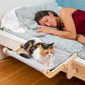 Cama hamaca para gatos Nuzzo sujeta junto a la cama con gato descansando