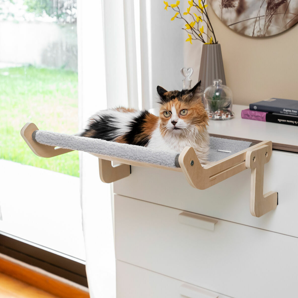 Cama hamaca para gatos Nuzzo sujeta junto a la cama con gato descansando