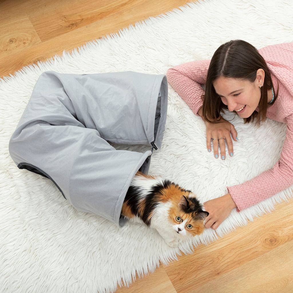 Túnel plegable para gatos Nuzzo en un salón con un gato asomado