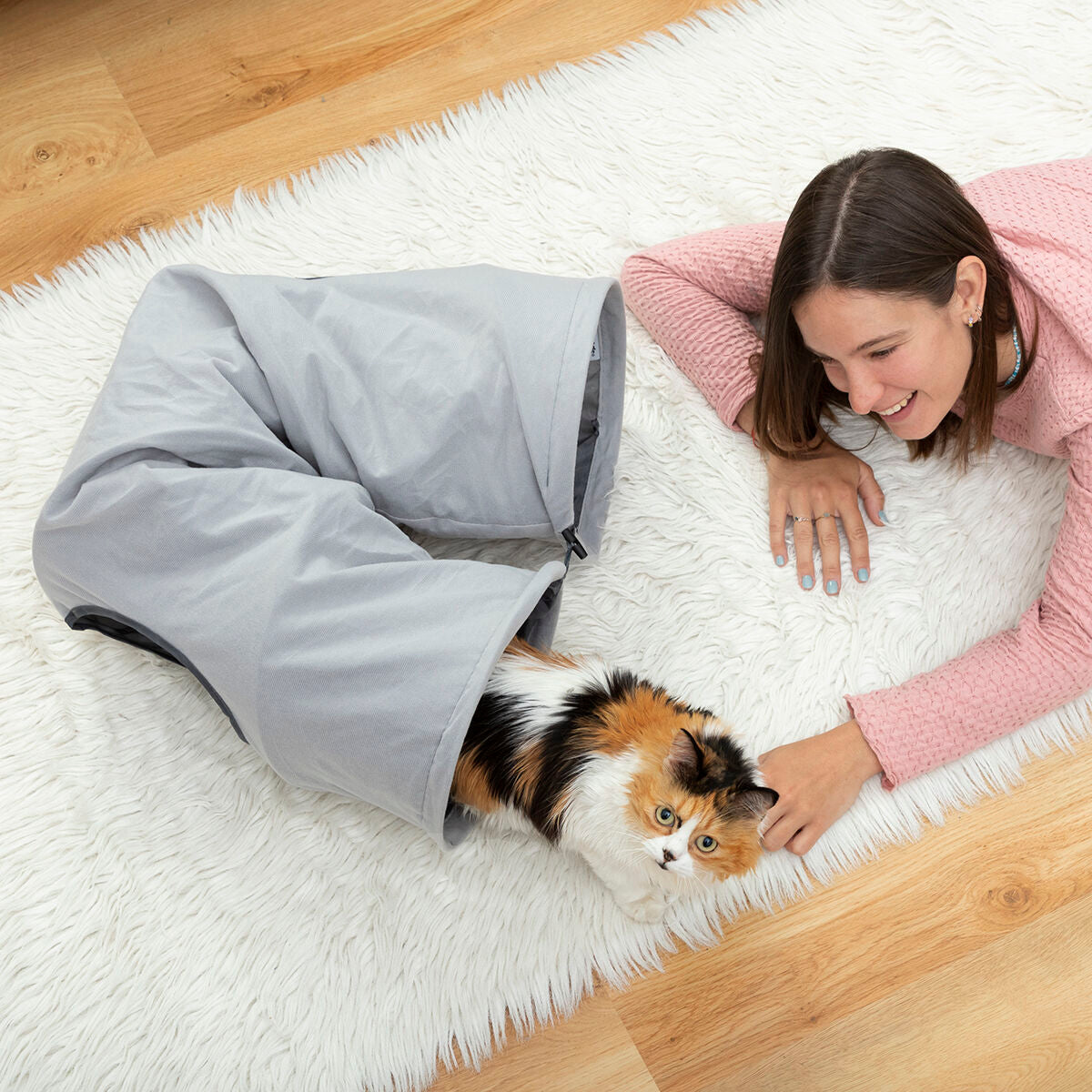 Túnel plegable para gatos Nuzzo en un salón con un gato asomado